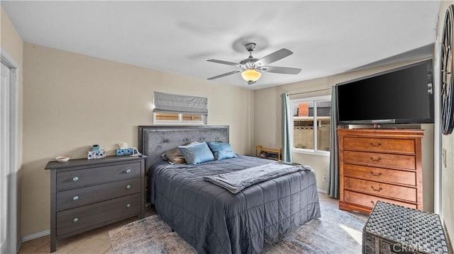 bedroom with light tile patterned floors, baseboards, and a ceiling fan