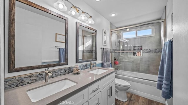 bathroom featuring a sink, tasteful backsplash, wood finished floors, and toilet