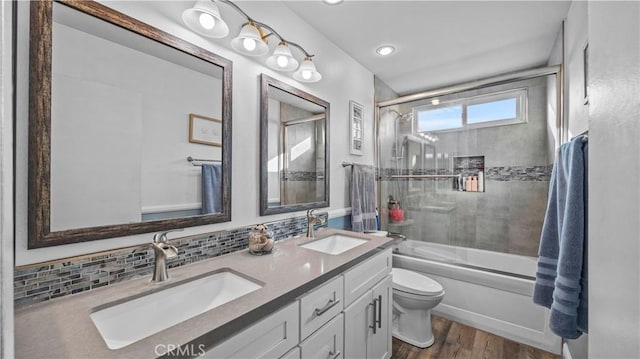 full bathroom featuring a sink, enclosed tub / shower combo, toilet, and wood finished floors