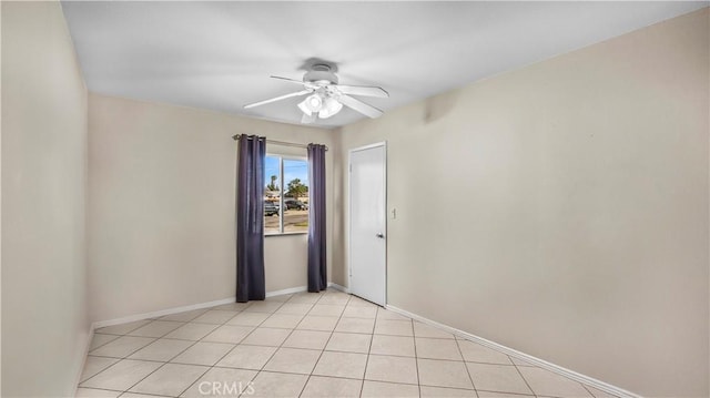 spare room featuring light tile patterned floors, ceiling fan, and baseboards