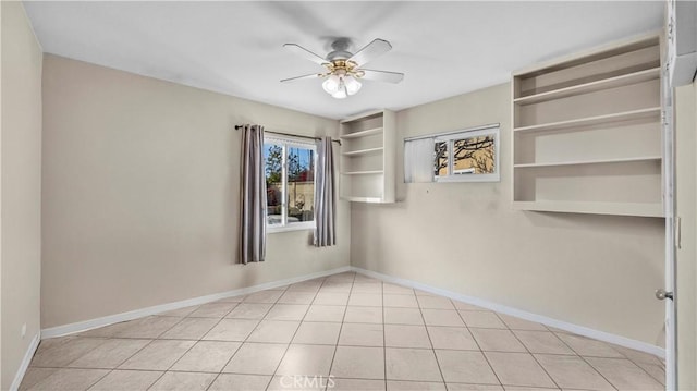 empty room with a ceiling fan, baseboards, and light tile patterned flooring