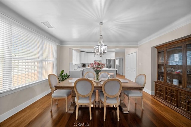 dining area with wood finished floors, visible vents, baseboards, an inviting chandelier, and crown molding