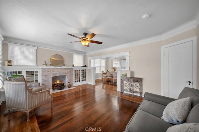 living area with ornamental molding, a fireplace, wood finished floors, and a ceiling fan