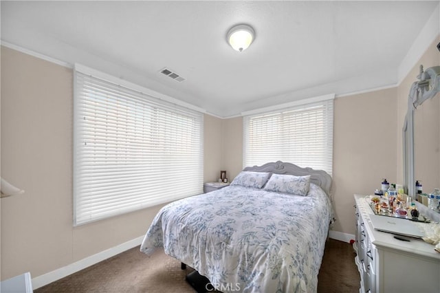 bedroom with crown molding, dark colored carpet, visible vents, and baseboards