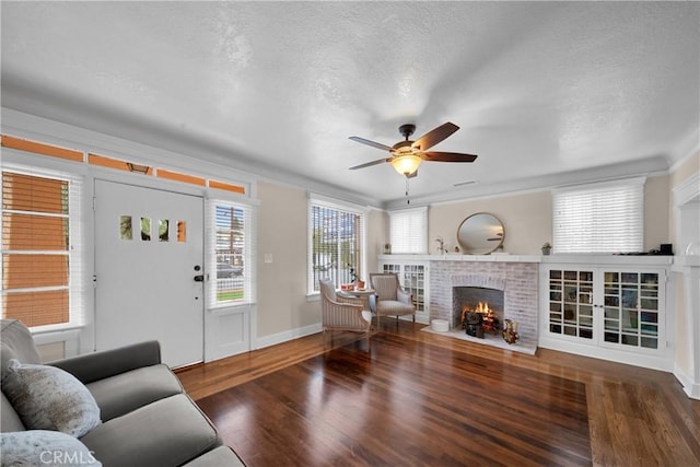 living area with a textured ceiling, ceiling fan, a brick fireplace, and wood finished floors