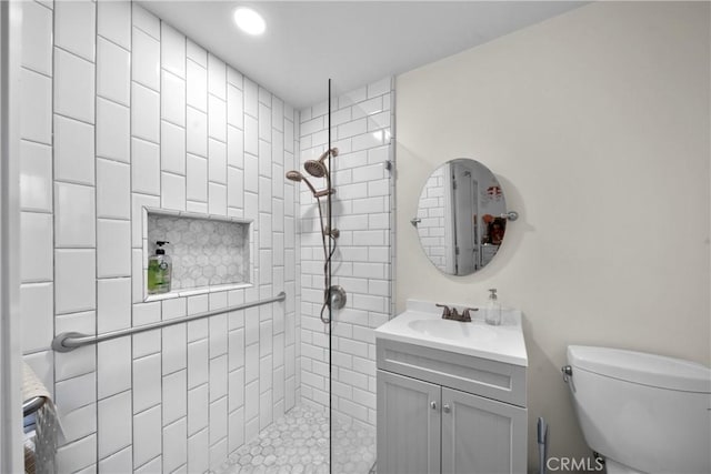 bathroom featuring a walk in shower, toilet, and vanity