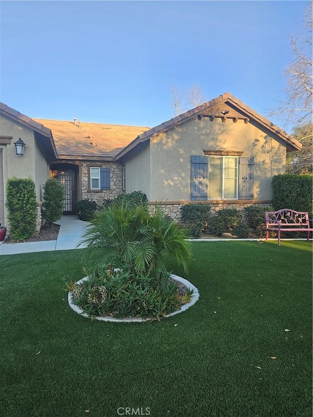 view of front of home featuring a front yard, stone siding, and stucco siding