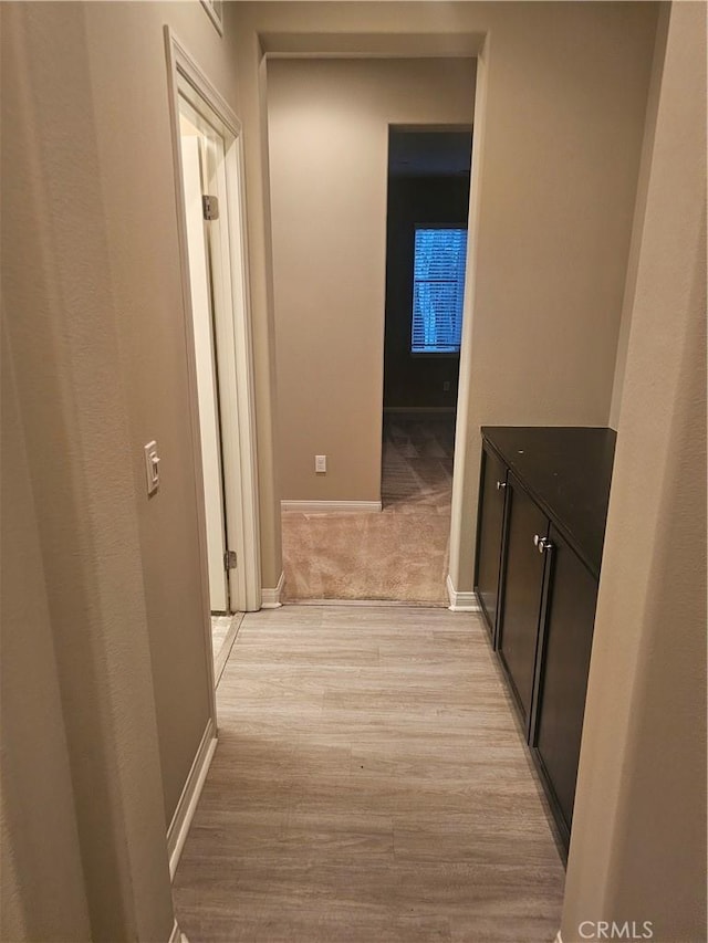 corridor with light wood-style flooring and baseboards