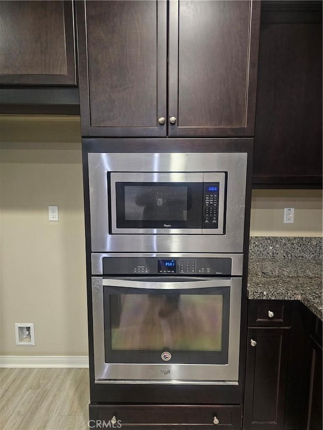 room details with dark brown cabinetry, stone countertops, light wood-type flooring, and baseboards