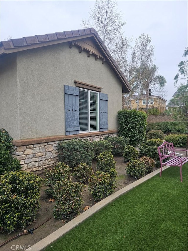 view of home's exterior with stucco siding and a lawn