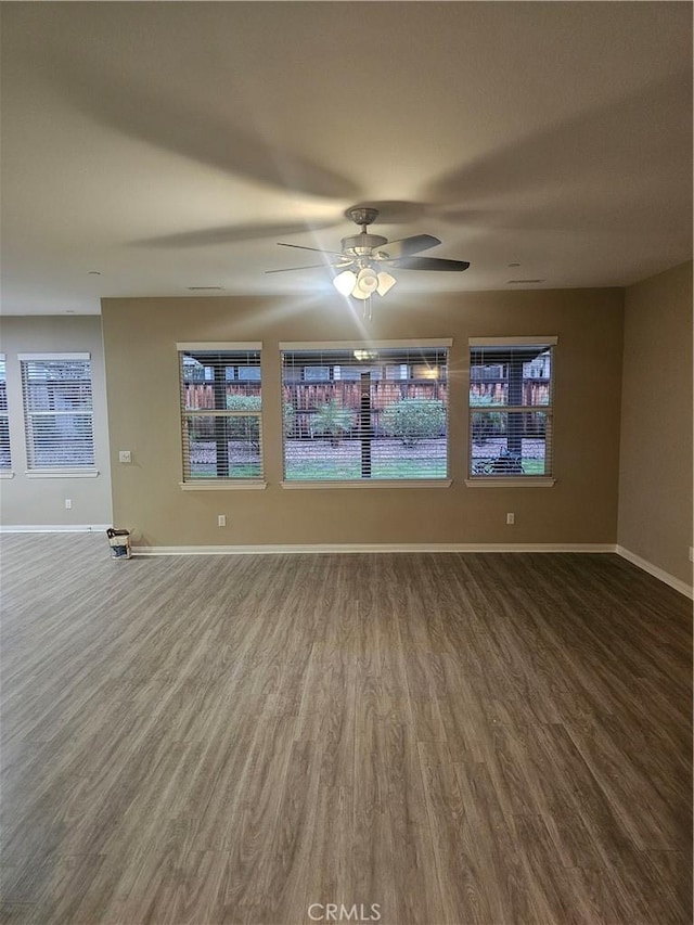 empty room featuring baseboards, wood finished floors, and a ceiling fan