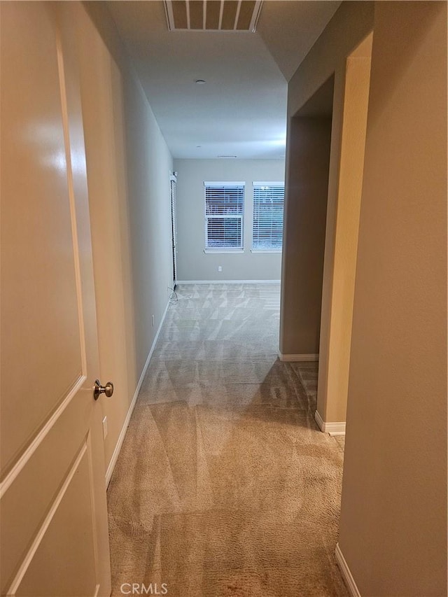 hallway with carpet flooring, baseboards, and visible vents