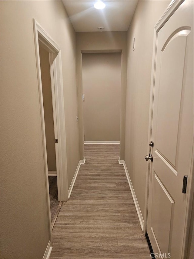 corridor with baseboards and wood finished floors