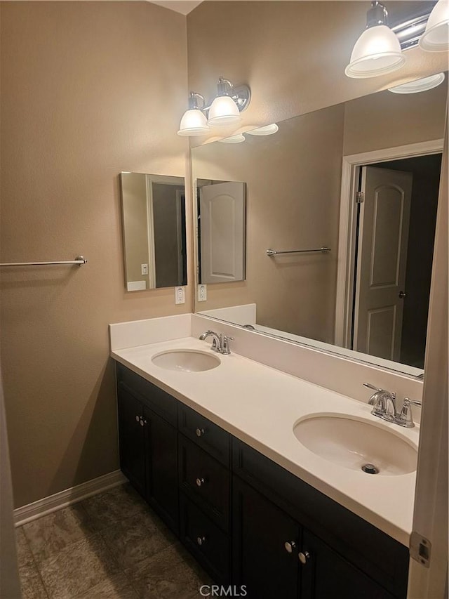 bathroom featuring double vanity, baseboards, and a sink