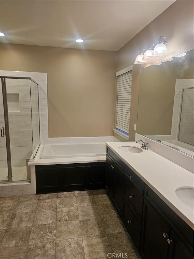 bathroom featuring a sink, a garden tub, a stall shower, and double vanity