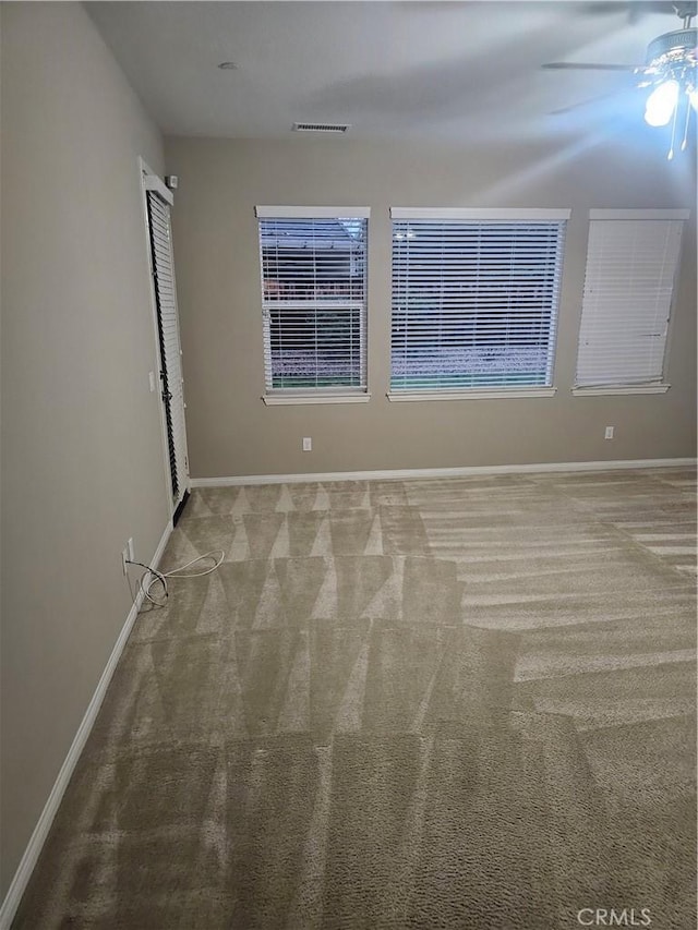 unfurnished room with carpet flooring, visible vents, baseboards, and ceiling fan