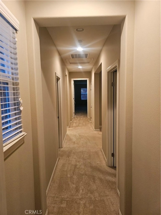 hallway featuring baseboards and light carpet