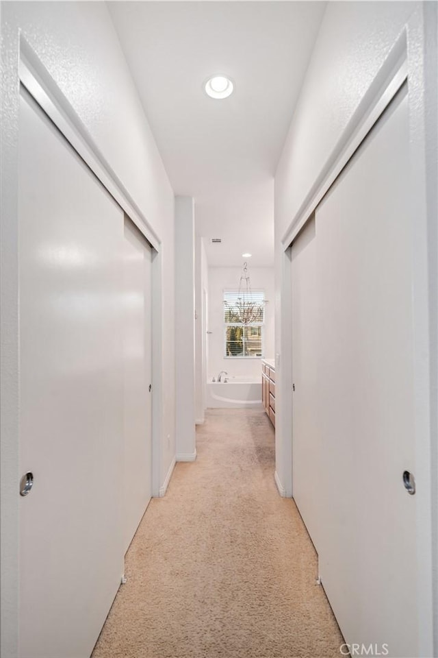 hall featuring light carpet and baseboards