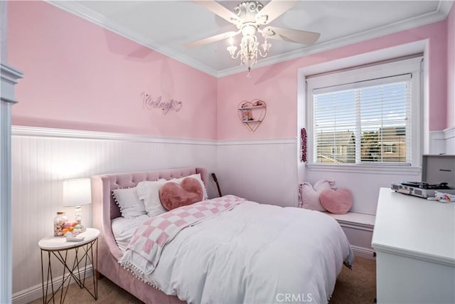 carpeted bedroom with ceiling fan, crown molding, and wainscoting