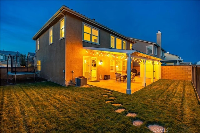 back of house with a patio, cooling unit, a fenced backyard, a yard, and a trampoline