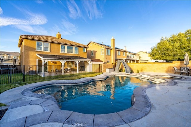 view of pool with a patio, a water slide, cooling unit, a fenced backyard, and a fenced in pool