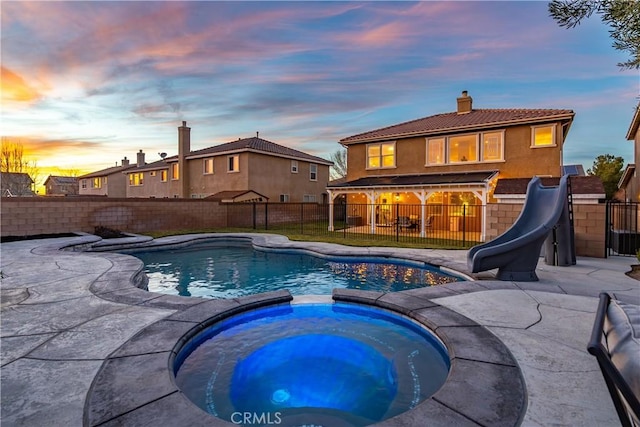 view of swimming pool featuring a patio area, a water slide, and a fenced backyard