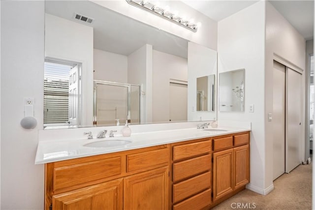 full bath with visible vents, a sink, a shower stall, and double vanity