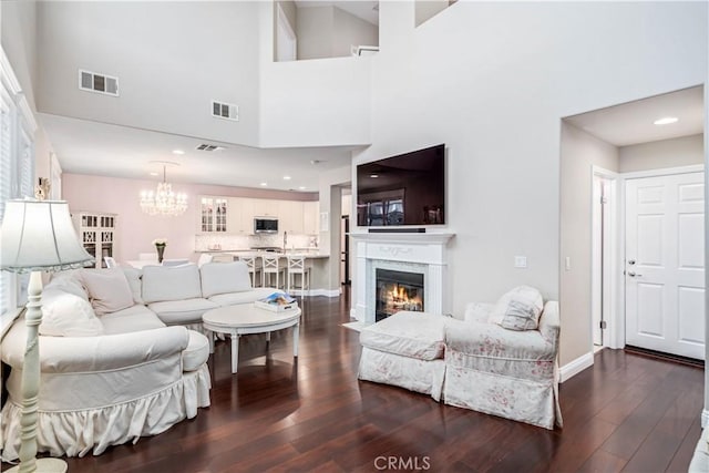 living room with baseboards, visible vents, dark wood-type flooring, and a glass covered fireplace