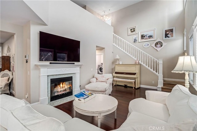 living room featuring baseboards, a glass covered fireplace, stairway, wood finished floors, and a high ceiling