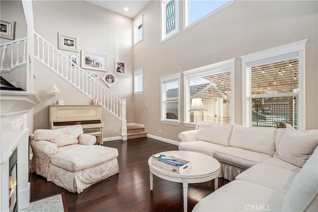 living area with recessed lighting, baseboards, stairs, a lit fireplace, and dark wood-style floors