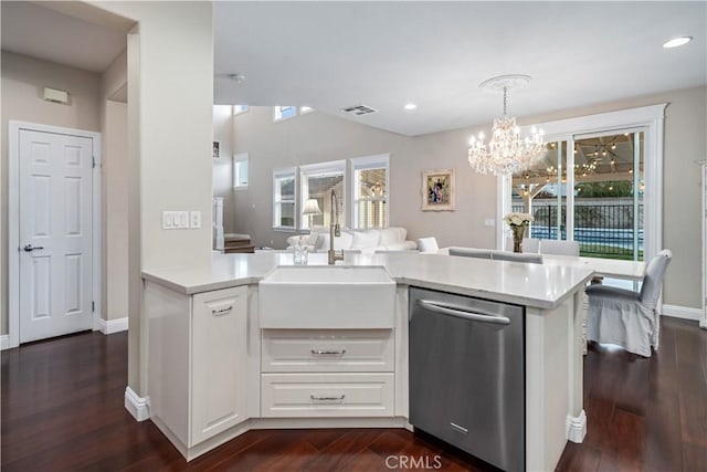 kitchen featuring visible vents, dishwasher, dark wood-style floors, light countertops, and a sink