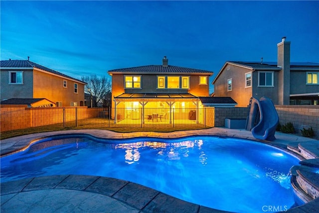 view of pool featuring a patio area, a fenced backyard, a fenced in pool, and a water slide