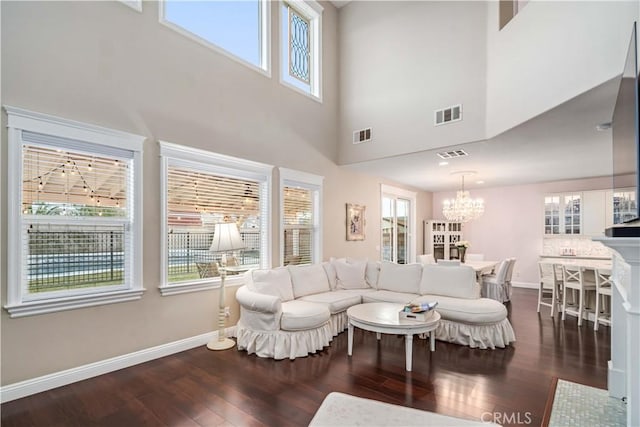 living area featuring dark wood-type flooring, visible vents, a notable chandelier, and baseboards