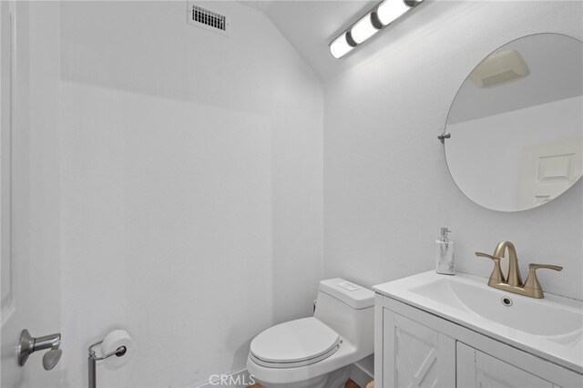 bathroom with lofted ceiling, visible vents, vanity, and toilet