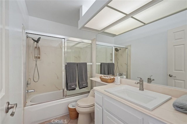 bathroom featuring toilet, bath / shower combo with glass door, and vanity