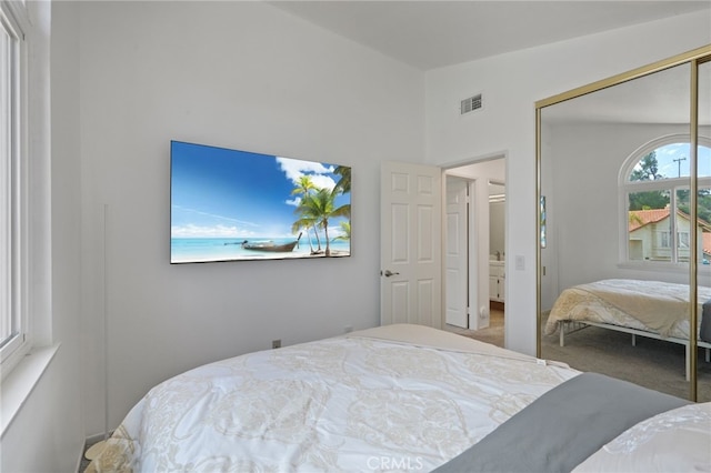 carpeted bedroom featuring vaulted ceiling, a closet, and visible vents