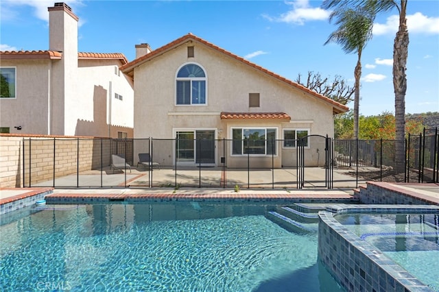 view of pool featuring a patio, a gate, fence, and a pool with connected hot tub