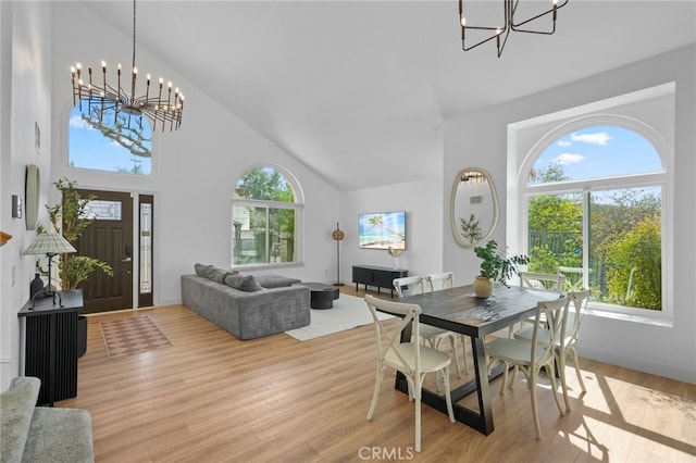 dining area with high vaulted ceiling, light wood finished floors, and an inviting chandelier