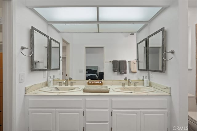 bathroom with double vanity, a sink, toilet, and connected bathroom