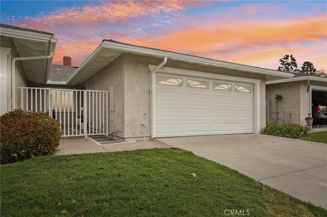 exterior space with driveway, a lawn, an attached garage, and stucco siding