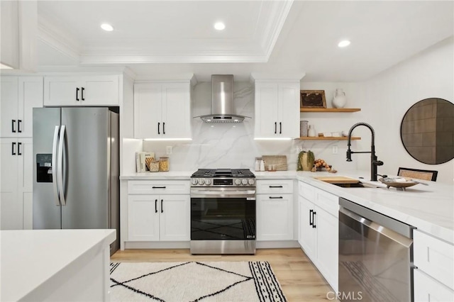 kitchen featuring stainless steel appliances, a sink, light countertops, ornamental molding, and wall chimney exhaust hood