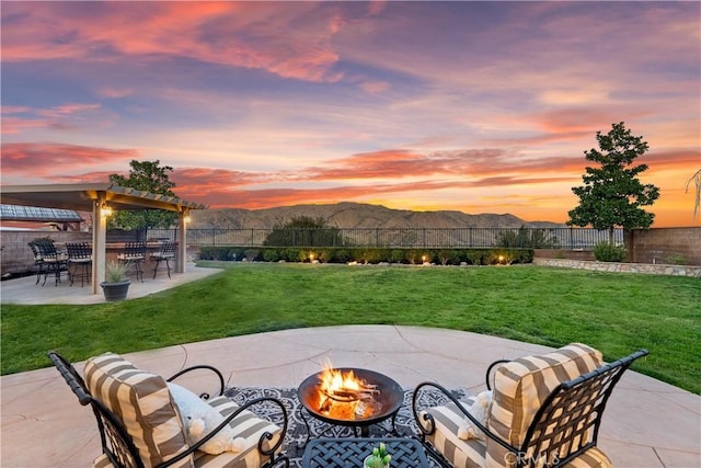 view of patio / terrace with fence, a mountain view, and an outdoor fire pit