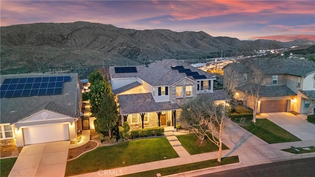 view of front of property featuring a front lawn, covered porch, driveway, a garage, and a mountain view