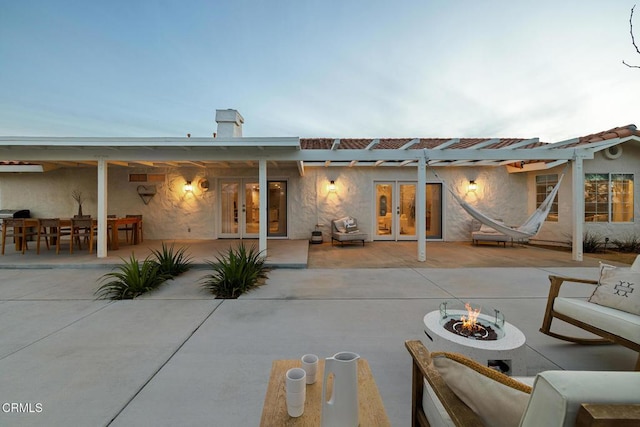 back of property featuring french doors, a fire pit, stucco siding, and a patio area