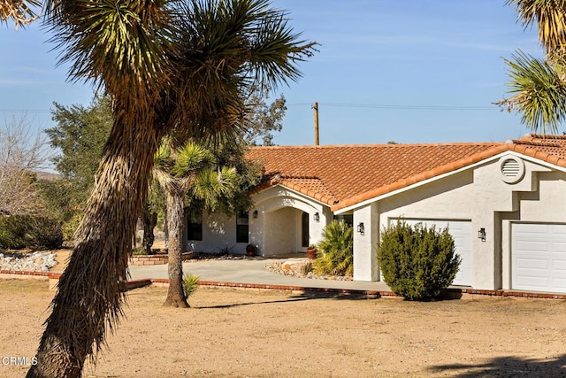 view of front facade featuring a tiled roof, stucco siding, and an attached garage