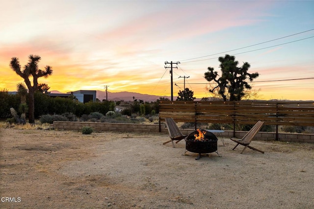 yard at dusk with a fire pit and fence