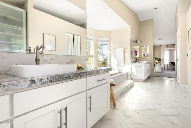 bathroom with plenty of natural light, marble finish floor, vanity, and a garden tub