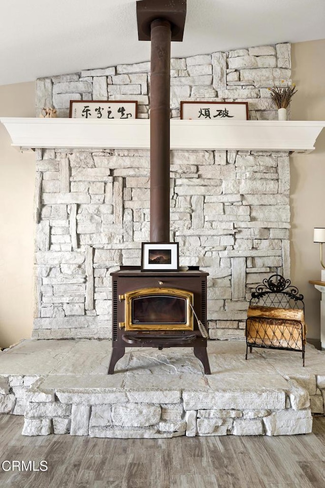 interior details featuring a wood stove and wood finished floors