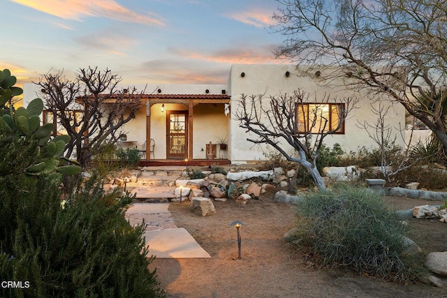 exterior space with covered porch, a tiled roof, and stucco siding