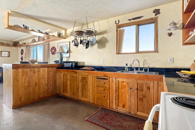 kitchen featuring finished concrete flooring, white electric range oven, brown cabinets, a peninsula, and a sink